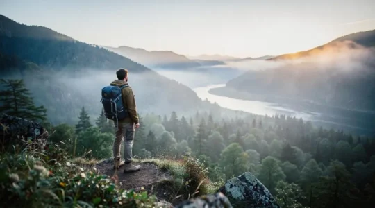 Voyageur contemplant une vallée sauvage préservée au lever du jour, symbole d'un écotourisme à impact mesurable
